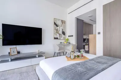 a white bedroom with a large flat screen tv on the wall at Frank Porter - Grove by Eman in Dubai