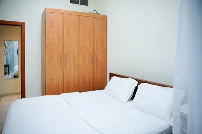 a bedroom with a white bed and a wooden cabinet at Two Bedroom with Full marina view in Dubai