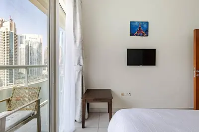 a bedroom with a bed and a tv and a window at Two Bedroom with Full marina view in Dubai