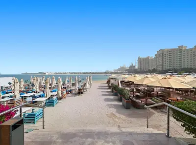 a beach with chairs and umbrellas and the ocean at Beachfront Boho Bliss Direct Beach Access in Dubai