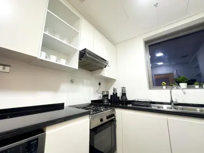 a white kitchen with a sink and a stove at Greenery Haven 2 Bed plus Study in Damac Hills in Dubai