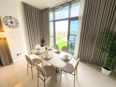 a dining room with a table and chairs and a large window at Greenery Haven 2 Bed plus Study in Damac Hills in Dubai
