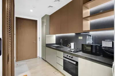 a kitchen with wooden cabinets and a black counter top at Stylish Studio with Burj Khalifa Views in Dubai