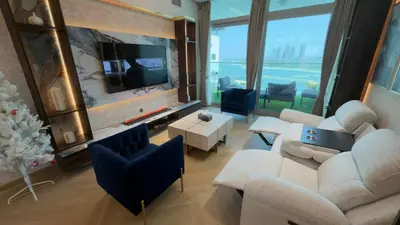 a living room with a couch and chairs and a tv at Beachside Palm Jumeirah 1 Br apartment in Dubai