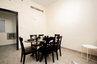a dining room with a table and black chairs at Brand New 2BHK Fully Furnished Apartment in Warsan in Dubai