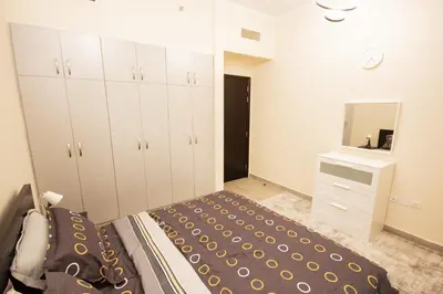 a bedroom with a bed and a dresser and a mirror at Brand New 2BHK Fully Furnished Apartment in Warsan in Dubai