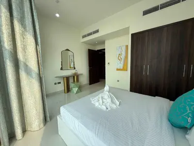 a bedroom with a white bed with a wooden cabinet at Spacious Fully Furnished 6BR Villa in Damac Hill2 in Dubai