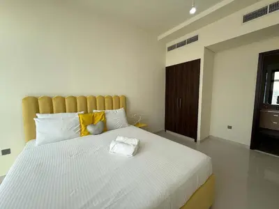 a bedroom with a large white bed with yellow pillows at Spacious Fully Furnished 6BR Villa in Damac Hill2 in Dubai