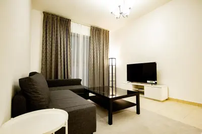 a living room with a couch and a tv at Newly Furnished 1BHK Apartment in Maya Residency in Dubai