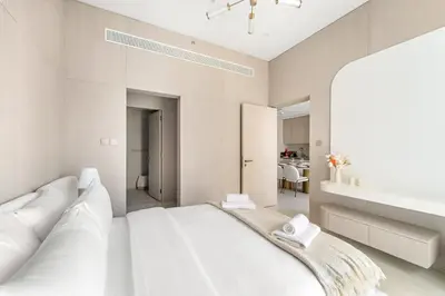 a bedroom with a white bed and a bathroom at VayK - Refined 1 BD Apartment in JVC in Dubai