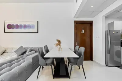 a living room with a couch and a table and chairs at Peaceful 1BR with Balcony at Elite Residence Dubai in Dubai
