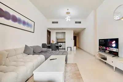 a white living room with a couch and a tv at Peaceful 1BR with Balcony at Elite Residence Dubai in Dubai