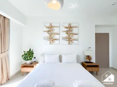 a white bedroom with a white bed and white walls at Skyline Escape 2BR Stay with balcony, Pool & Gym in Dubai