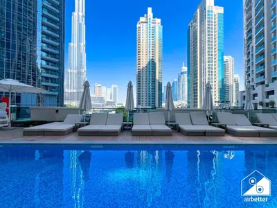 a pool with chairs and a view of the city at Skyline Escape 2BR Stay with balcony, Pool & Gym in Dubai