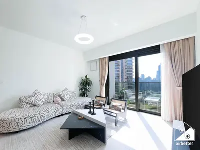 a living room with a couch and a large window at Skyline Escape 2BR Stay with balcony, Pool & Gym in Dubai