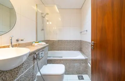 a bathroom with a tub and a sink and a toilet at Zapbed House-Modern Studio Apartment in Dubai Sports City in Dubai