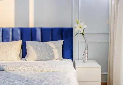 a bed with a blue headboard and a vase with a flower at Luxury 2BR in Dubai Marina Man 1014 in Dubai