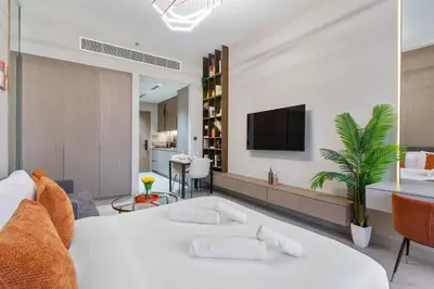 a bedroom with a white bed and a tv on a wall at Chic & Sleek Studio in Westwood Grande in Dubai