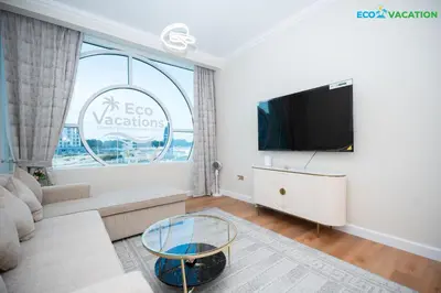 a living room with a large window and a tv at Eco-Luxe Retreat - Minutes from Global Village in Dubai