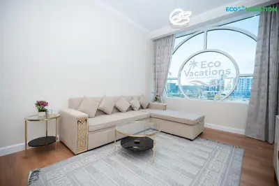 a living room with a couch and a large window at Eco-Luxe Retreat - Minutes from Global Village in Dubai