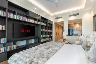 a bedroom with a large bed with a tv and bookshelves at White Sage Discovery Gardens Renovated Studio next to Metro in Dubai