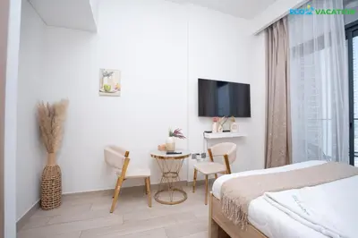 a bedroom with a bed and a table and a tv at Riviera Haven Boutique Stay with Wooden Charm in Dubai