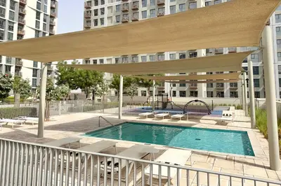 a patio with a pool and a large umbrella at PVH - Posh 2BR with 1 Queen Bed Plus 1 Single Bed - Collective 2-0 in Dubai