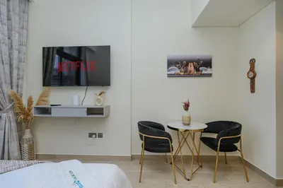 a room with two chairs and a table and a tv at The Riviera Nook Cozy Stay in Dubai in Dubai