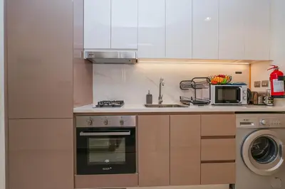 a kitchen with a sink and a stove and a microwave at The Riviera Nook Cozy Stay in Dubai in Dubai