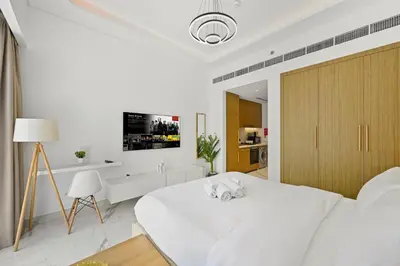 a white bedroom with a bed and a tv on the wall at Estudio Coral en Dubai By BeBalmy in Dubai