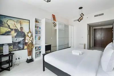 a bedroom with a large white bed and a book shelf at Beachside Bliss With Stylish 2BR with Panoramic View in Dubai