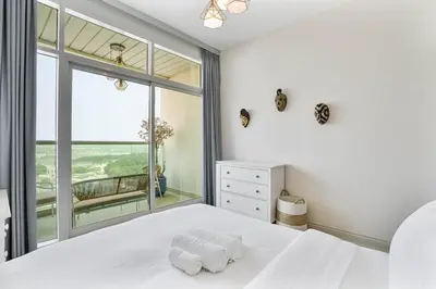a bedroom with a white bed and a large window at Beachside Bliss With Stylish 2BR with Panoramic View in Dubai