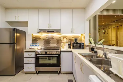 a kitchen with white cabinets and a stainless steel refrigerator at The Urban Retreat Elegant 3BR Townhouse Villanova in Dubai