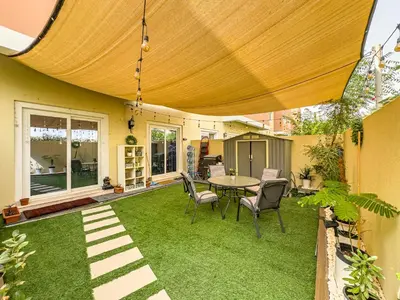 a patio with grass and a table and chairs at The Urban Retreat Elegant 3BR Townhouse Villanova in Dubai