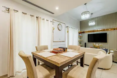 a dining room with a table and chairs and a couch at The Urban Retreat Elegant 3BR Townhouse Villanova in Dubai