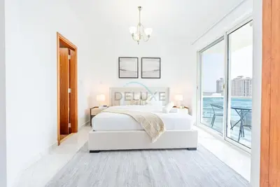 a white bedroom with a bed and a large window at Lake-View Apartment Near City Centre Meaisem Mall, Just Minutes from Dubai Autodrome and ICC Cricket Stadium - The Crescent A, Dubai Production City by Deluxe Holiday Homes in Dubai