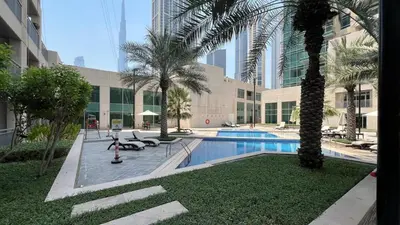 a swimming pool with palm trees and a building at Luxury 2BR in Downtown w Iconic Burj Khalifa View Burj Views 303 in Dubai