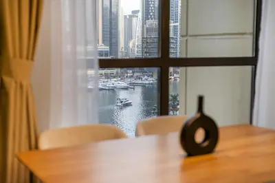 a table with chairs and a window with a view of a harbor at Luxurious 3BHK w Marina Views & Pool Table by dPie Sadaf 408 in Dubai