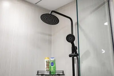 a shower in a bathroom with a shower head and two bottles at Luxury 2 BR in Al Barsha Opalz Danube by dpie A312 in Dubai
