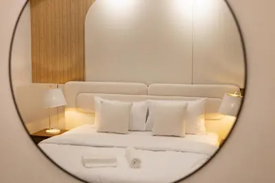 a mirror reflection of a bed with white sheets and pillows at Luxury 4 BHK Villa in JVC by dPie in Dubai