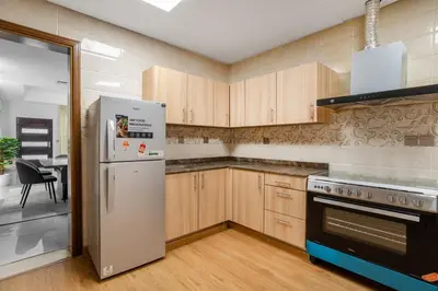 a kitchen with wooden cabinets and a white refrigerator at Luxury 4 BHK Villa in JVC by dPie in Dubai