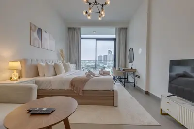 a bedroom with a large bed and a living room at Oxford Terraces, JVC - Studio Apartment - Allsopp & Allsopp in Dubai