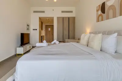 a large white bed with a television in a bedroom at Oxford Terraces, JVC - Studio Apartment - Allsopp & Allsopp in Dubai