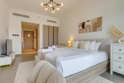 a bedroom with a large white bed and a couch at Oxford Terraces, JVC - Studio Apartment - Allsopp & Allsopp in Dubai