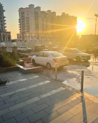 two cars parked in a parking lot with the setting sun at Modern Studio Apartment in Dubai Sports City in Dubai