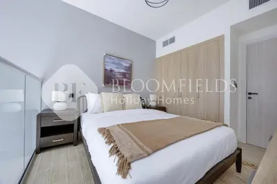 a white bedroom with a bed and a night stand at Bloomfields Deluxe 1br Rukan in Dubai