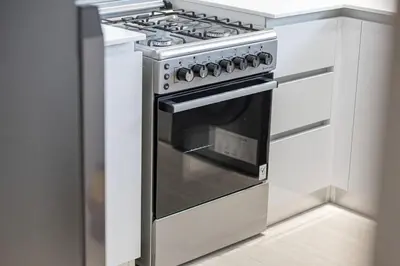 a stainless steel stove in a kitchen with white cabinets at 1BR Luxury Stay With Pool, Gym and Skyline View in Dubai