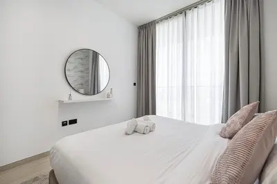 a bedroom with a large white bed with a mirror at 1BR Luxury Stay With Pool, Gym and Skyline View in Dubai