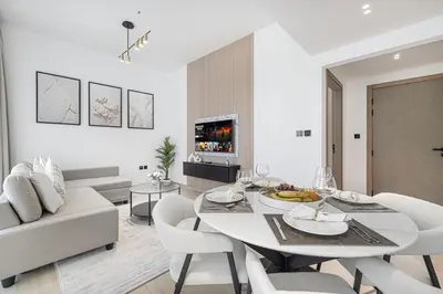 a white dining room with a white table and chairs at 1BR Luxury Stay With Pool, Gym and Skyline View in Dubai