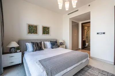 a white bedroom with a large bed with blue pillows at Elegant 2-Bedroom Apartment with Stunning City and Water Views in Dubai